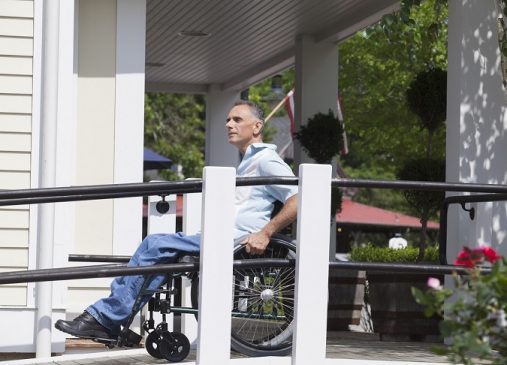 Man in wheelchair uses ramp to access building