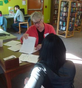 Two women sit at a library desk during a free legal clinic