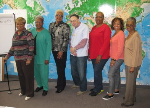 seven adults stand in a room during an encore training session.