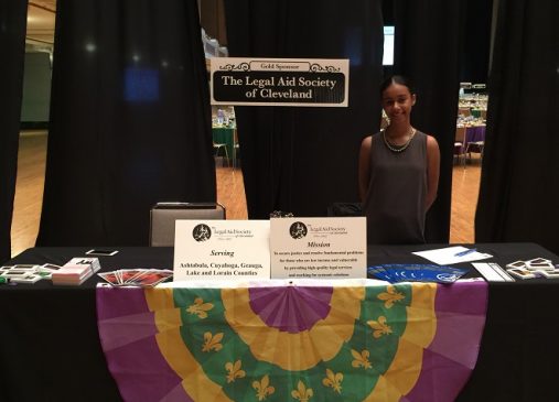 Caitly Reynoso stands behind Legal Aid Society information table at event