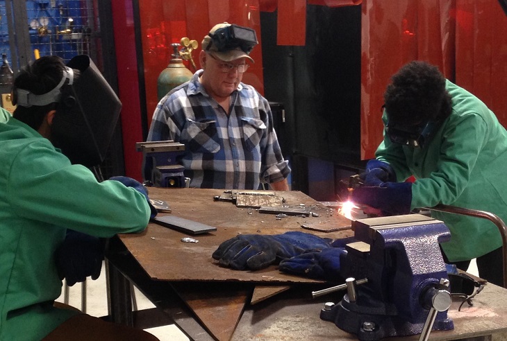 Gary Dudich, retired Journeyman Ironworker and Technical Corps Program Member assists welding students at Max S. Hayes High School with practice welds.