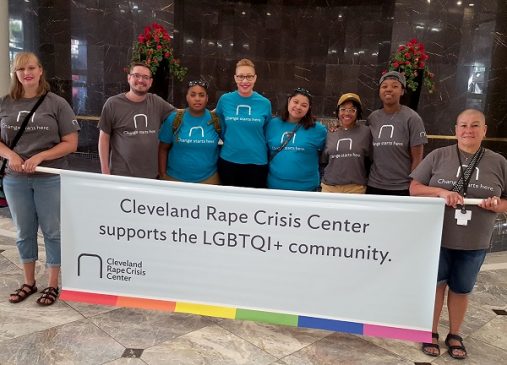 Group of students stands in front of a banner that reads Cleveland Rape Crisis Center supports the LGBTQI+ community.