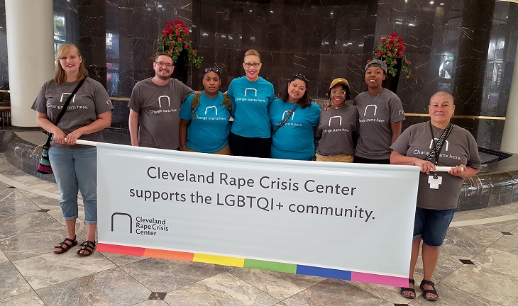 Group of students stands in front of a banner that reads Cleveland Rape Crisis Center supports the LGBTQI+ community.