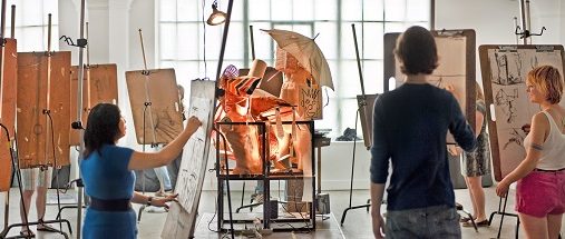 Art students stand at easels in a studio
