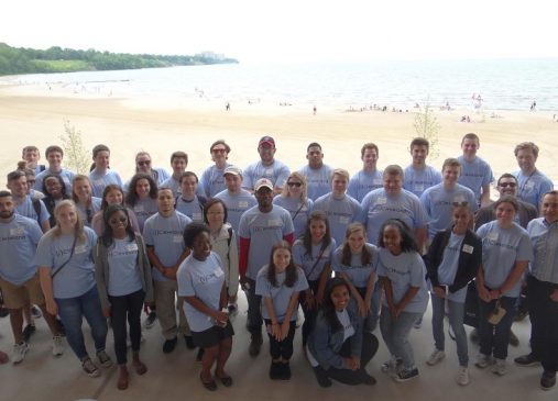 Large group of people pose for a picture on Edgewater Beach wearing Cleveland Leadership Center shirts