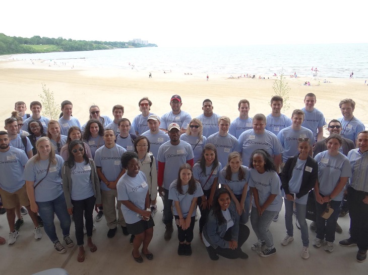 Large group of people pose for a picture on Edgewater Beach wearing Cleveland Leadership Center shirts