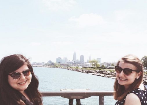 Katie and another girl stand in front of Lake Erie with Cleveland skyline in distance