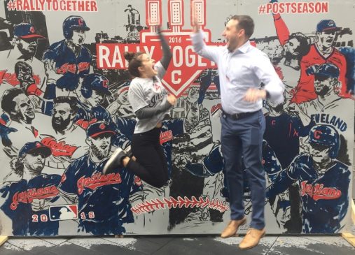 Tabitha and her brother jump and high-five in front of a Cleveland Indians mural