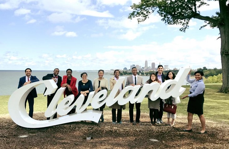 Cleveland Foundation fellows stand in front of Cleveland script sign with Lake Erie and Cleveland skyline behind