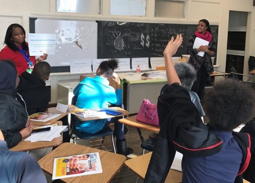 Two True2U mentors lead an exercise in front of a classroom