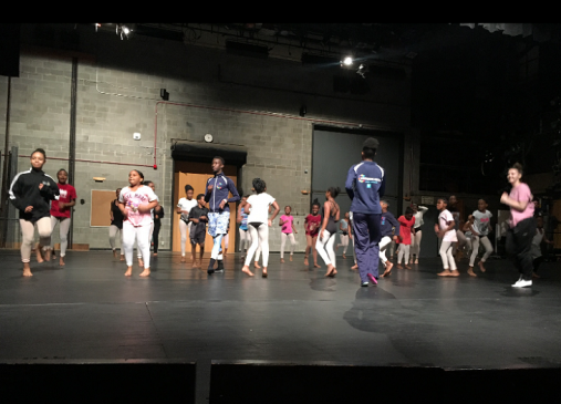 A group of students practice a dance routine on stage