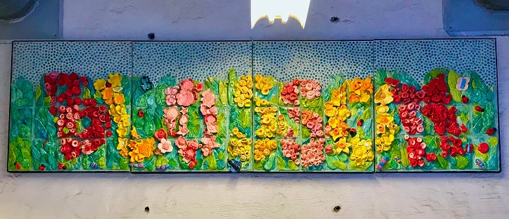 Mixed media work of art spells out the word blossom in flowers