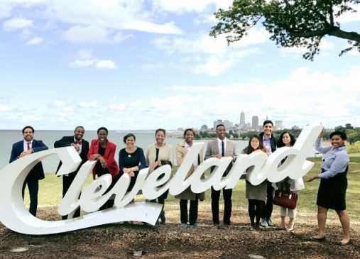 Public Service Fellows stand behind Cleveland script sign with skyline in background