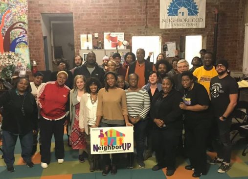 A group of grant recipients and neighbor up network members pose with Neighbor Up yard sign