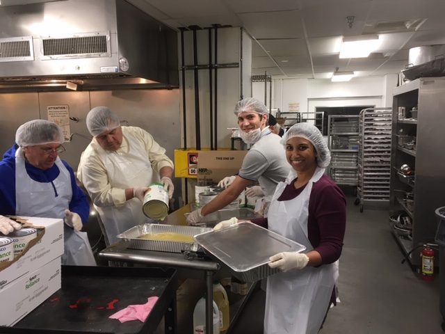 Four members of the Cleveland Club of Washington, D. C. transfer apple sauce from can to pan in the Club's effort to deliver balanced meals to Washington's hungry.