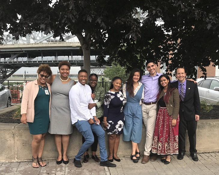 The 2017-18 Public Service Fellows pose for a photograph outdoors with their host site supervisors
