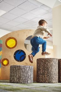 A young boy jumps from a small tree stump to a larger stump inside the Meadows exhibit at the Children's Museum of Cleveland