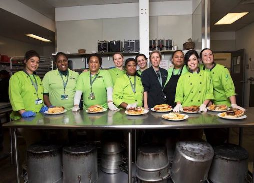 a group of women in chef jackets stand in commercial kitchen