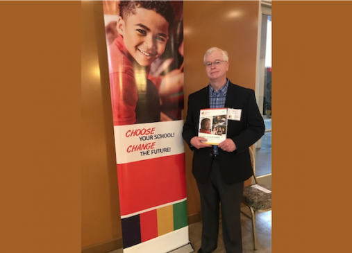 Tim Angbrandt stands in front of Cleveland Transformation Alliance Poster