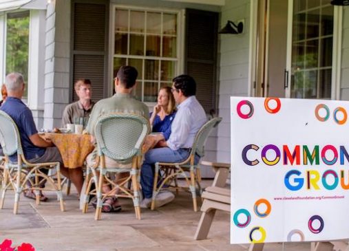 a group of people sit around a table on a porch
