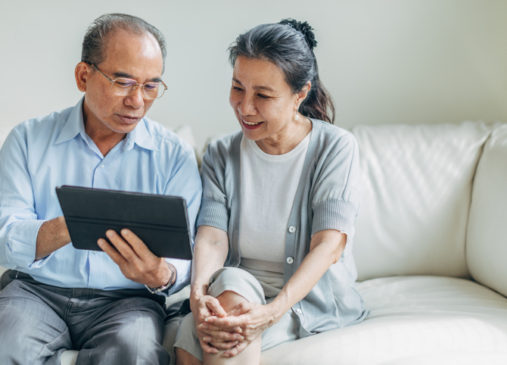 Man and woman, senior married couple using digital tablet at home together.