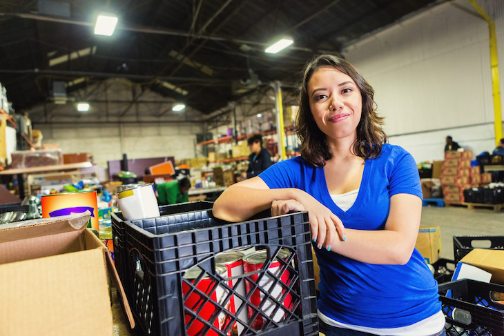 A woman stands inside a food bank warehouse