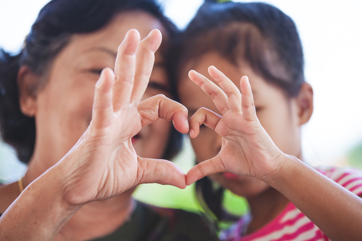 mother and little girl making heart shape with hands together with love