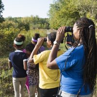 Young people outdoors using binoculars