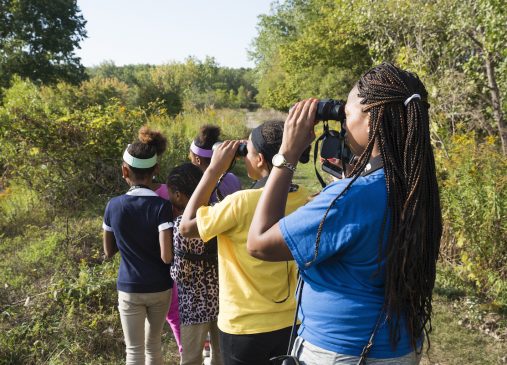 Young people outdoors using binoculars