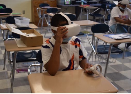 Boy sits at desk wearing virtual reality head set