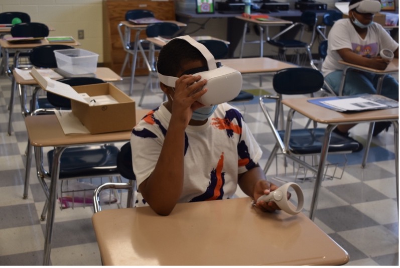 Boy sits at desk wearing virtual reality head set