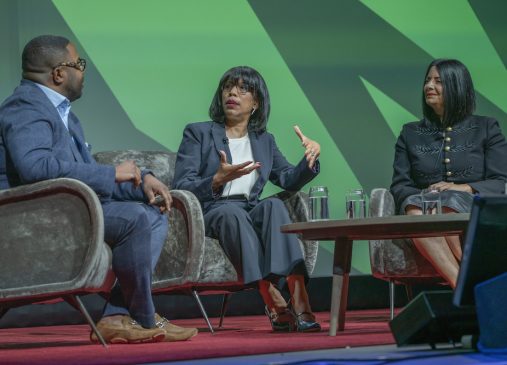 Three panelists sit onstage in chairs
