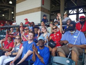 A group of people seated at Progressive Field cheers during a baseball game