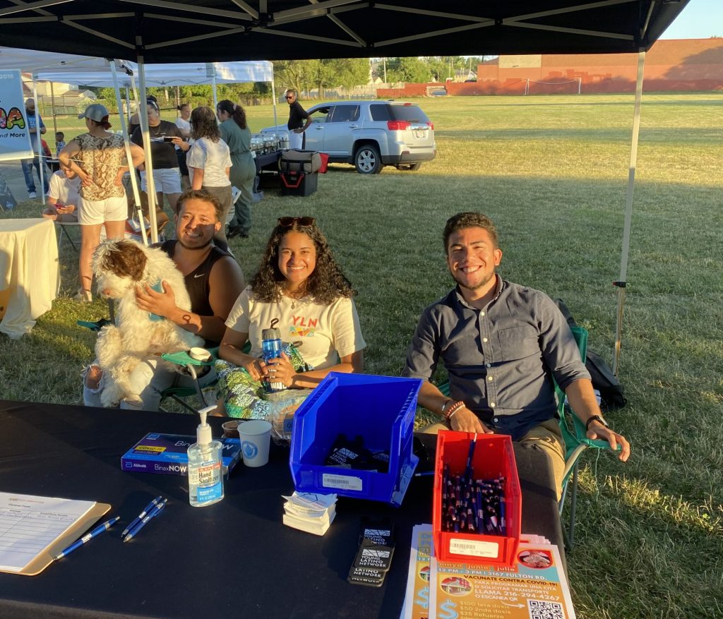 Emily Reyes pictured sitting at YLN information table at outdoor event