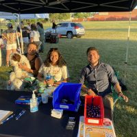 Emily Reyes pictured sitting at YLN information table at outdoor event