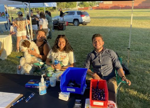 Emily Reyes pictured sitting at YLN information table at outdoor event