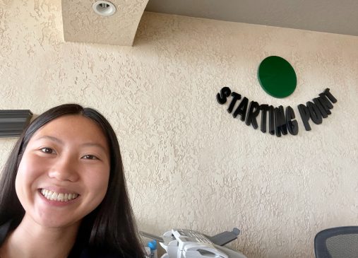 Joy Mason taking a selfie in front of a wall with Starting Point's logo on it