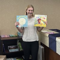 Photo of summer intern Elizabeth Keller holding up books